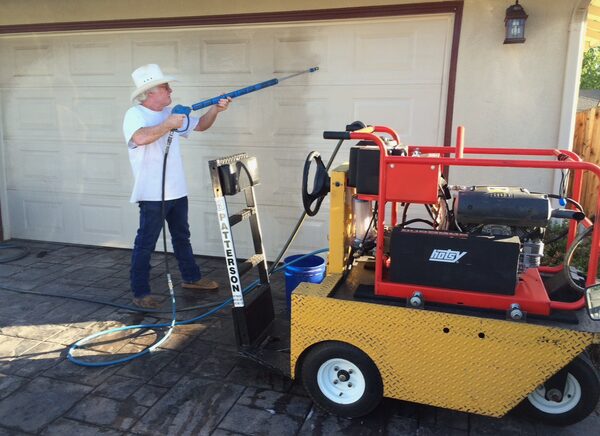 Paul power washing concrete near a residential garage