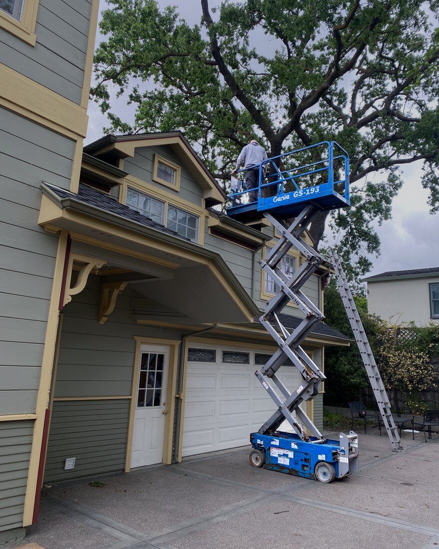 Paul working from a lift beside a residential roofline