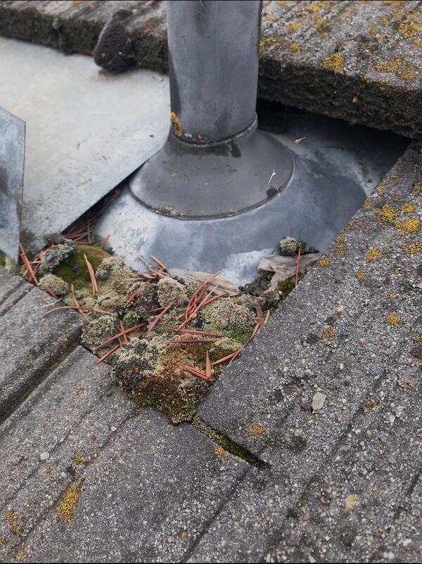 Pipe and flashing detail on a tile roof with debris nearby